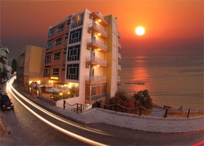 Ahiram Hotel lit up at dusk on the seafront road into Byblos